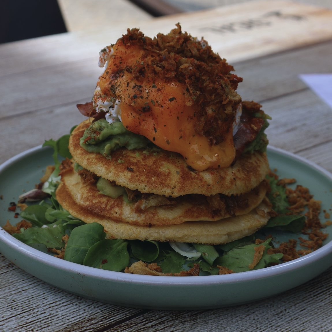 Three homemade pancakes, cheddar, bacon, guacamole, poached egg, fried onion